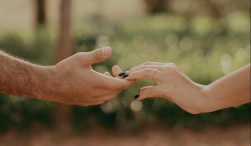 casal de mãos dadas e um anel de noivado